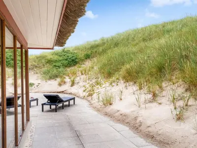a patio with a table and a bench on the beach at Holiday Home Zora - 100m from the sea by Interhome in Harboør