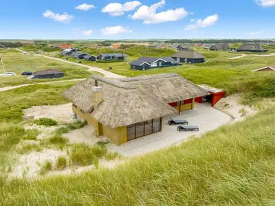 a house on the beach with a thatched roof at Holiday Home Zora - 100m from the sea by Interhome in Harboør