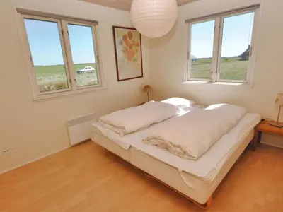 a bedroom with a bed in a room with windows at Holiday Home Ernbiorn - from the sea by Interhome in Harboør