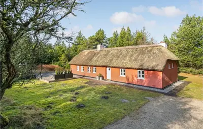 a red house with a thatched roof on a yard at Amazing Home In Pandrup in Pandrup