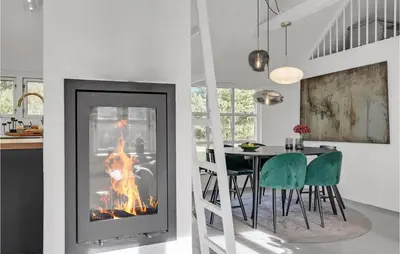 a fireplace in a kitchen with a table and chairs at Amazing Home In Pandrup in Pandrup