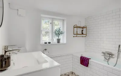 a white bathroom with a tub and a sink at Amazing Home In Pandrup in Pandrup