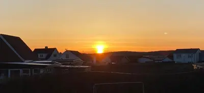 a sunset over houses in a residential neighborhood at 200 m til havet - fri adgang til svømmehal in Thyborøn