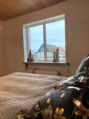 a bedroom with a bed and a large window at 200 m til havet - fri adgang til svømmehal in Thyborøn