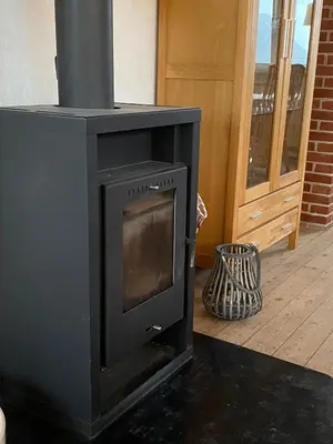 a black wood stove in a room with a door at 200 m til havet - fri adgang til svømmehal in Thyborøn