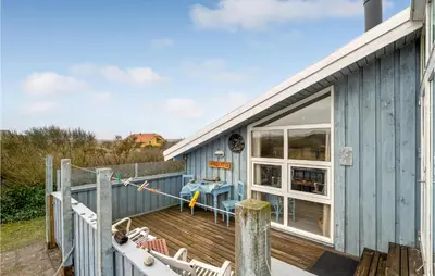 a blue house with a deck with chairs at 3 Bedroom Lovely Home In Lemvig in Lemvig