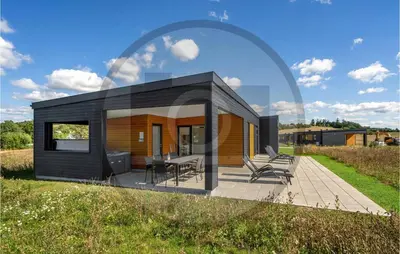 a small black house with a deck in a field at 4 Bedroom Beautiful Home In Løgstrup in Løgstrup