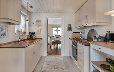a kitchen with white cabinets and a dining room at Lovely Home In Pandrup With Wifi in Pandrup