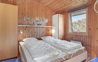 two beds in a wooden room with a window at Beautiful Home In Løkken With Wifi in Løkken