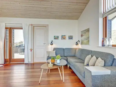 a living room with a blue couch and a table at Holiday Home Arngrim - 100m from the sea by Interhome in Torsted