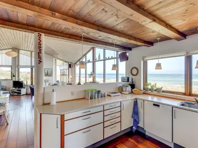 a kitchen with white cabinets and a view of the ocean at Holiday Home Arngrim - 100m from the sea by Interhome in Torsted
