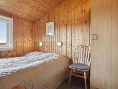 a bedroom with a bed and a chair in it at Holiday Home Siri - 400m from the sea by Interhome in Thisted