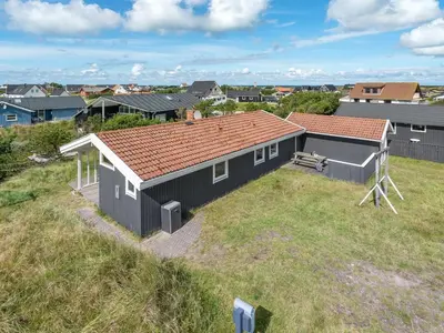 a black house with a red roof on a field at Holiday Home Siri - 400m from the sea by Interhome in Thisted