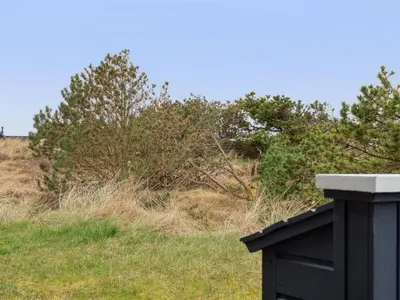 a black fence in a field with trees and grass at Holiday Home Siri - 400m from the sea by Interhome in Thisted