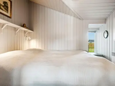 a bedroom with a large white bed and a window at Holiday Home Marissa - 200m from the sea by Interhome in Torsted