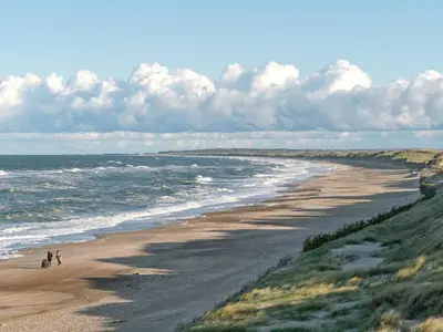 two people walking on a beach near the ocean at Holiday Home Marissa - 200m from the sea by Interhome in Torsted