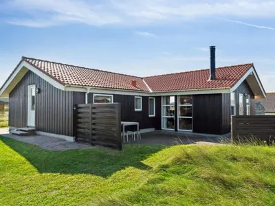 a black house with a table in a yard at Holiday Home Marissa - 200m from the sea by Interhome in Torsted