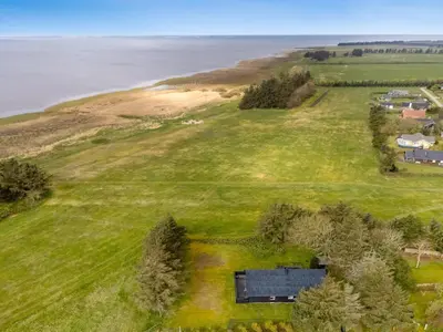 an aerial view of a house on a grassy hill next to the ocean at Holiday Home Aleida - 100m to the fjord by Interhome in Vemb