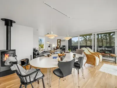 a living room with a table and chairs and a fireplace at Holiday Home Aleida - 100m to the fjord by Interhome in Vemb