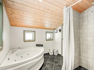 a white tub in a bathroom with a wooden ceiling at Holiday Home Kai - 500m to the fjord by Interhome in Struer