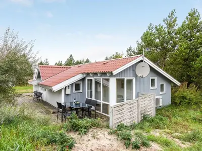 a small white house with a table in front of it at Holiday Home Biriel - 1km from the sea by Interhome in Thisted