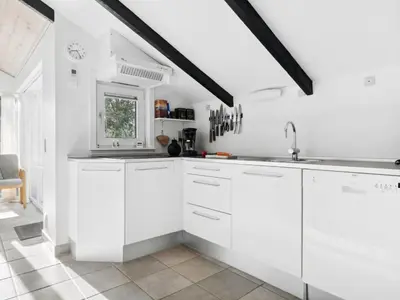 a white kitchen with white cabinets and a window at Holiday Home Biriel - 1km from the sea by Interhome in Thisted