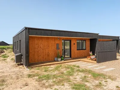 a small black house with a wooden facade at Holiday Home Trpana - 1-6km from the sea by Interhome in Thisted