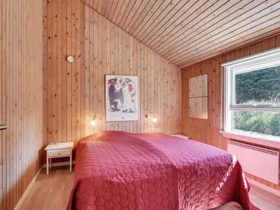 a bedroom with a red bed in a wooden room at Holiday Home Bente - 800m from the sea by Interhome in Thisted