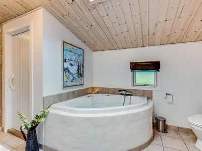 a large white tub in a bathroom with a toilet at Holiday Home Emeline - 1-7km from the sea by Interhome in Thisted
