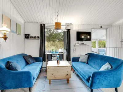 a living room with two blue couches and a table at Holiday Home Gundina - 2km from the sea by Interhome in Thisted