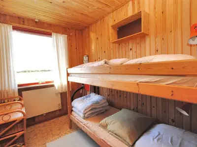two bunk beds in a wooden room with a window at Holiday Home Neven - 900m from the sea by Interhome in Torsted