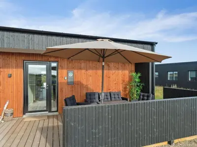 an umbrella on a deck with chairs under it at Holiday Home Kasper - 1-8km from the sea by Interhome in Thisted