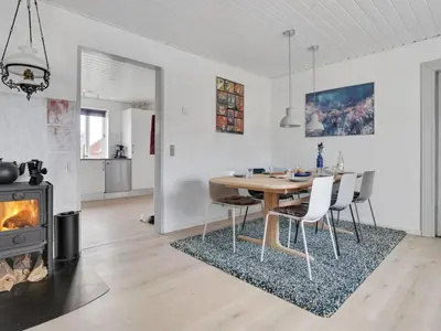 a dining room with a table and chairs and a fireplace at Holiday Home Thilla - 100m from the sea by Interhome in Thisted