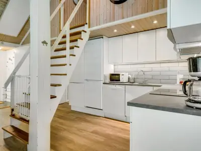 a kitchen with white cabinets and a spiral staircase at Holiday Home Eisa - 300m to the fjord by Interhome in Øsløs