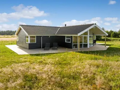 a small black house with two chairs in a field at Holiday Home Sulki - 3-5km from the sea by Interhome in Frøstrup