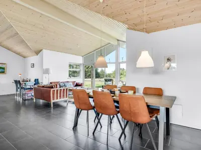 a dining room and living room with a table and chairs at Holiday Home Sulki - 3-5km from the sea by Interhome in Frøstrup