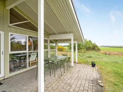 a screened in porch with a table and chairs at Holiday Home Aameek - 3km from the sea by Interhome in Frøstrup