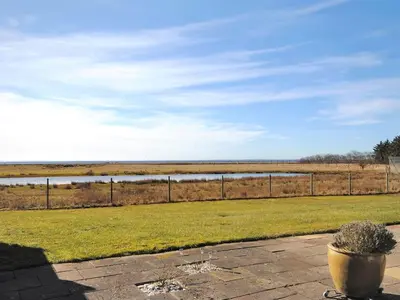 a field of grass with a fence and a body of water at Apartment Rejhana - 500m to the fjord by Interhome in Øsløs