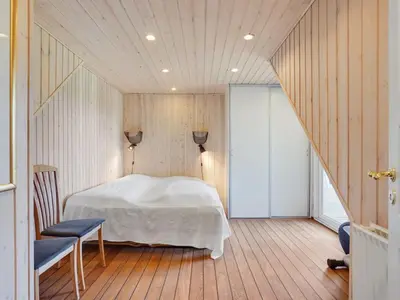 a bedroom with a white bed and a wooden floor at Holiday Home Gertrudis - 2km to the fjord by Interhome in Frøstrup