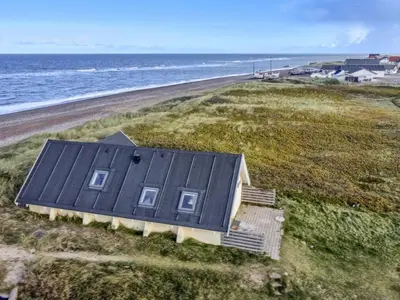 a house with a black roof on the beach at Holiday Home Ebba - 25m from the sea by Interhome in Frøstrup