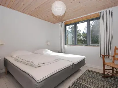 a bedroom with a bed and a chair and windows at Holiday Home Margrethe - 1-1km from the sea by Interhome in Bedsted Thy