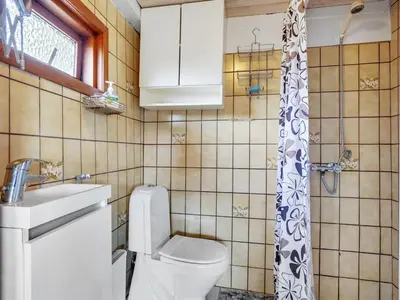 a small bathroom with a toilet and a sink at Holiday Home Leocadia - 150m to the fjord by Interhome in Øsløs