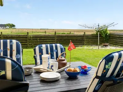 a wooden table with chairs and a table with food on it at Holiday Home Leocadia - 150m to the fjord by Interhome in Øsløs