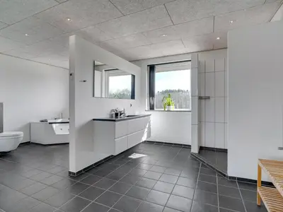a bathroom with a sink and a toilet and a window at Holiday Home Markhild - 300m to the fjord by Interhome in Sønder Ydby