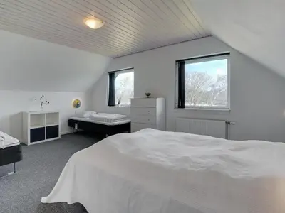 a white bedroom with a bed and two windows at Holiday Home Markhild - 300m to the fjord by Interhome in Sønder Ydby