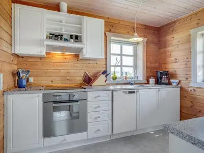 a kitchen with white appliances and wooden walls at Holiday Home Bjarnger - 200m from the sea by Interhome in Frøstrup