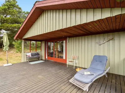 a deck with a chair and a house at Holiday Home Atreju - 2km from the sea by Interhome in Bedsted Thy