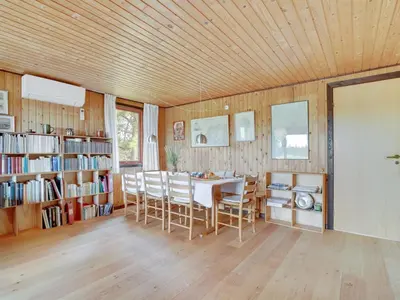 a dining room with a table and chairs and bookshelves at Holiday Home Atreju - 2km from the sea by Interhome in Bedsted Thy