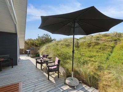 a patio with a table and an umbrella at Holiday Home Wulfhard - 400m from the sea by Interhome in Frøstrup