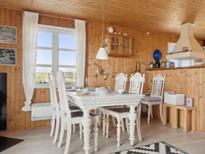 a dining room with a white table and chairs at Holiday Home Wulfhard - 400m from the sea by Interhome in Frøstrup